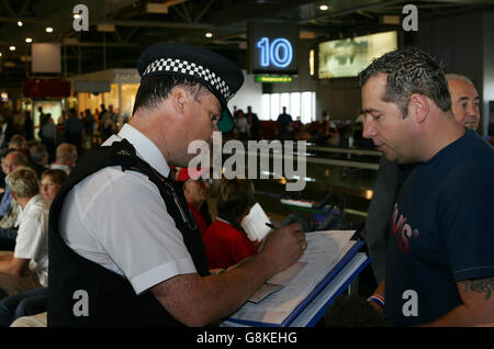 Polizeibeamte sprechen bei einem Check-in am Terminal 4 des Londoner Flughafens Heathrow mit englischen Fans. Zwei Menschen wurden gestoppt, als die Polizei eine nationale Operation startete, um bekannte und mutmaßliche Störenfriede zu verhindern, die morgen gegen Dänemark in Kopenhagen in das England-Fußballfreundschaftssemble reisen. Stockfoto