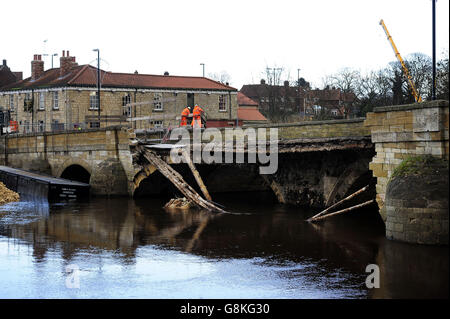 Die Bauarbeiten an der historischen Brücke sind im Gange, da eine provisorische Fußgängerbrücke errichtet wird, um den Fußgängerzugang über den Fluss Wharfe in Tadcaster, North Yorkshire, zu ermöglichen, nachdem die 300 Jahre alte Straßenbrücke am 29. Dezember bei den Weihnachtsfluten eingestürzt war und die Stadt in zwei Hälften teilte. Stockfoto