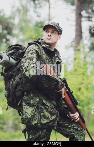 junger Soldat oder Jäger mit Gewehr im Wald Stockfoto