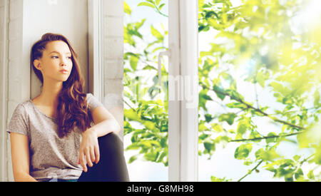 traurig ziemlich junges Mädchen sitzt auf der Fensterbank Stockfoto