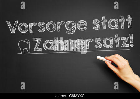 Hand, schreibt in Deutsch "Vorsorge Statt Zahnersatz!" (Vorsorge statt Zahnersatz) auf Tafel Stockfoto