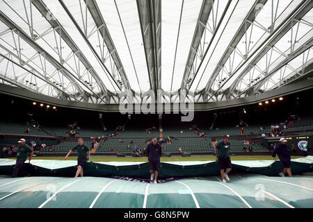 Bodenpersonal entfernen der Abdeckungen auf dem Centre Court nach geschlossenem Dach an Tag drei der Wimbledon Championships bei den All England Lawn Tennis and Croquet Club, Wimbledon. Stockfoto