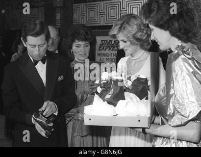 Der Prinz und die Prinzen von Wales sehen sich während einer Gala-Aufführung von „Starlight Express“ im Apollo Victoria Theatre, London, ein paar Rollschuhe an, die für ihre Söhne bestimmt sind. Stockfoto