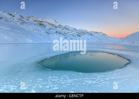 Frost, Erstellen von ungewöhnlichen Formen in der Mitte des Sees Bianco am Bernina erleuchtet durch das Licht des Sonnenaufgangs Schweiz Europa Stockfoto