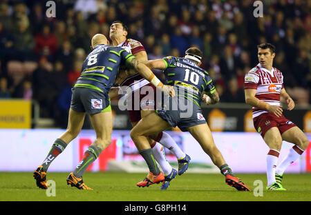 Ben Flower von Wigan Warriors wird von Keith Galloway von Leeds Rhinos (links) und Adam Cuthbertson (rechts) während des ersten Utility Super League-Spiels im DW Stadium, Wigan, angegangen. Stockfoto