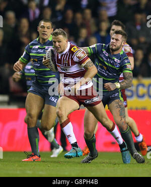 Dom Manfredi von Wigan Warriors überspringt beim ersten Spiel der Utility Super League im DW Stadium, Wigan, ein Tackle von Ryan Hall von Leeds Rhinos mit Zak Hardaker (rechts). Stockfoto