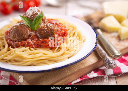 Ein Teller mit Spaghetti mit Fleischbällchen, garniert mit geriebenem Parmesan und Basilikum. Stockfoto