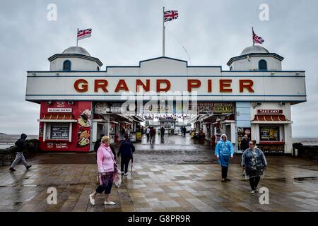 Menschen tragen Ponchos Fuß von der Grand Pier am Weston-super-Mare in Somerset als Regen und wind Teig Großbritanniens Westküste. Stockfoto