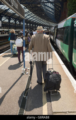 reifer Mann zu Fuß entlang Brighton Bahnsteig mit einem Wheelie-Beutel Stockfoto