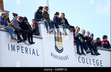 Boat Race Fans sitzen auf dem Dach des Imperial College Bootshauses, während sie darauf, für den Start der Frauen Regatta auf der Themse, London warten. Stockfoto