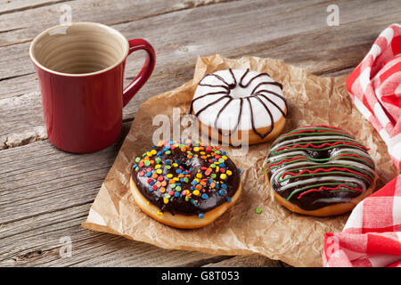 Donuts und Kaffeetasse auf Holztisch Stockfoto