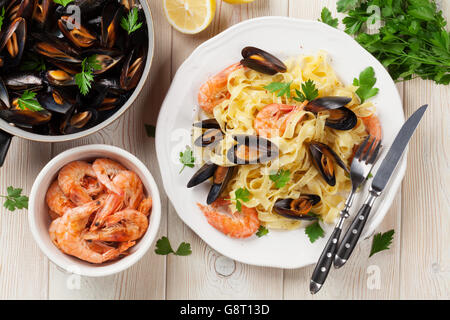Nudeln mit Meeresfrüchten auf hölzernen Tisch. Muscheln und Garnelen. Ansicht von oben Stockfoto