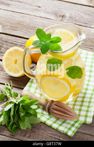 Limonade Krug mit Zitrone, Minze und Eis am Gartentisch Stockfoto