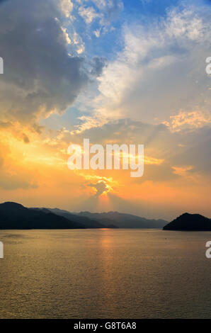 Schöne Landschaft während des Sonnenuntergangs über Bergketten am See in Srinakarin Damm, Provinz Kanchanaburi, Thailand Stockfoto