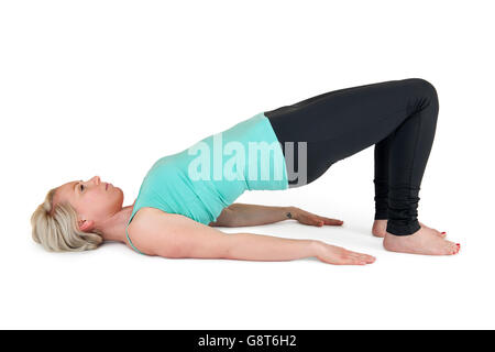 Ganzkörper-Blick auf eine junge, blonde Frau im Yoga Übung "schräge Brücke" vor weißem Hintergrund mit Licht Schatten Stockfoto