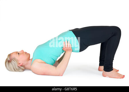 Gesamtansicht der Körper einer jungen blonden Frau in der Yogapraxis "-basierte Brücke" vor weißem Hintergrund mit Licht Schatten Stockfoto