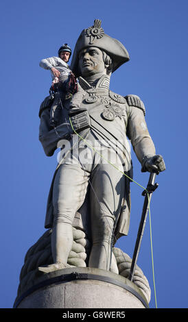 Luke Jones trifft sich mit der Statue von Lord Nelson, nachdem er und ein anderer Greenpeace-Aktivist die Nelson-Säule auf dem Londoner Trafalgar Square als Teil eines Morgens von Protesten bestiegen haben, um die Luftverschmutzung in Großbritannien hervorzuheben. Stockfoto