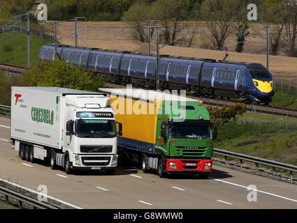 Transport von Lagerbeständen. Ein Hochgeschwindigkeits-Javelin-Zug, der die HS1-Eisenbahnlinie nutzt, passiert den Güterverkehr auf der M20 in der Nähe von Ashford in Kent. Stockfoto