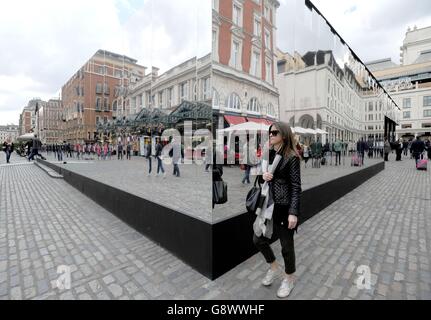 Die Menschen gehen an der neuen Installation Reflect London von Covent Garden vorbei, die 32,000 Quadratmeter Spiegel um die östliche Fassade des Market Building in Covent Garden im Zentrum von London wickelt und für rund acht Monate in Kraft sein wird. Das Verbergen wichtiger Bauwerke, da das denkmalgeschützte Gebäude seine neueste Transformation durchläuft. Stockfoto