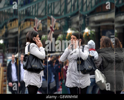 Eine Frau überprüft ihr Bild in der neuen Installation Reflect London von Covent Garden, die 32,000 Quadratmeter Spiegel um die östliche Fassade des Market Building in Covent Garden im Zentrum von London wickelt und für rund acht Monate in Kraft sein wird. Das Verbergen wichtiger Gebäude funktioniert, da das denkmalgeschützte Gebäude seine neueste Transformation durchläuft. Stockfoto