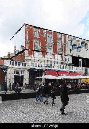 Die Menschen gehen an der neuen Installation Reflect London von Covent Garden vorbei, die 32,000 Quadratmeter Spiegel um die östliche Fassade des Market Building in Covent Garden im Zentrum von London wickelt und für rund acht Monate in Kraft sein wird. Das Verbergen wichtiger Bauwerke, da das denkmalgeschützte Gebäude seine neueste Transformation durchläuft. Stockfoto