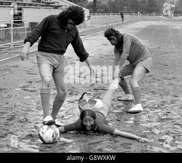 Prue spreißt sich im Schlamm aus, während sie in einem Fußballspiel für ein Team von Playboy-Hasen gegen 'Affen' aus dem Film Battle for the Planet of the Apes spielt. Das Spiel wurde in Hilfe des World Wildlife Fund. Stockfoto