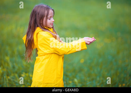 Entzückende Kleinkind Mädchen tragen, wasserdichte Jacke spielen im Freien bei Regen und sonnigen Tag Stockfoto