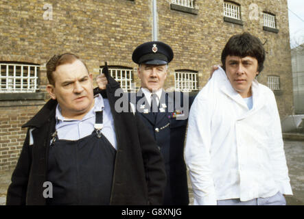 Old lag Fletcher (Ronnie Barker), Mitgefangener Godber (Richard Beckinsale) und Gefängnisbeamter Mackay (Fulton Mackay) während Drehorte für die Filmversion ihrer TV-Serie 'Porridge' im Chelmsford Gefängnis, die seit einem Brand im letzten Jahr leer war. Stockfoto