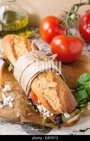 Tapeziert vegetarische Baguette u-Boot-Sandwich mit gegrillter Aubergine, Paprika und Feta-Käse auf Backpapier mit Tomaten serviert Stockfoto