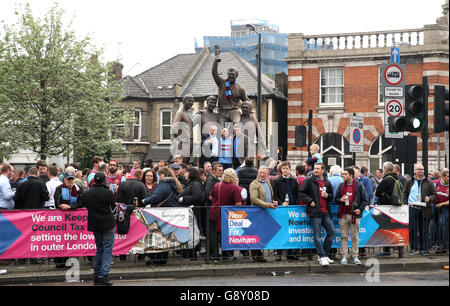 Fans versammeln sich um die Statue vor dem Upton Park mit Bobby Moore, Geoff Hurst, Ray Wilson und Martin Peters, die an Englands WM-Sieg 1966 vor dem Spiel der Barclays Premier League im Upton Park, London, erinnern. Stockfoto