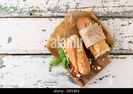 Zwei Hälfte vegetarische Baguette u-Boot-Sandwich mit gegrillter Aubergine, Paprika und Feta-Käse auf Backpapier über alte serviert Stockfoto