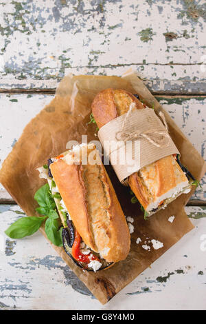 Zwei Hälfte vegetarische Baguette u-Boot-Sandwich mit gegrillter Aubergine, Paprika und Feta-Käse auf Backpapier über alte serviert Stockfoto