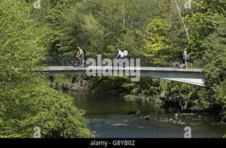 Im Kelvingrove Park in Glasgow fahren Menschen über eine Brücke über den Fluss Kelvin. Stockfoto