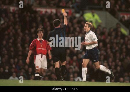 Gary Neville von Manchester United (links) sieht zu, während Schiedsrichter Paul Alcock (Mitte) Tottenham Hotspur's Jurgen Klinsmann (rechts) die gelbe Karte zeigt Stockfoto