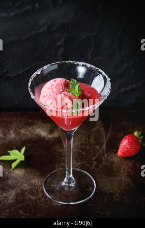 Cocktailglas Erdbeer Dessert mit Sorbet, serviert auf dunklem Hintergrund mit Erdbeeren, Himbeeren und Minze Behi gezuckert Stockfoto
