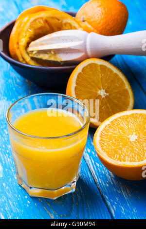 Frisch gepresster Orangensaft und Orangen auf blauen Holzbrett Stockfoto