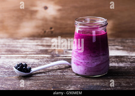 Köstliche hausgemachte Bio Smoothie mit gefrorenen Beeren in einem Glas auf Holztisch mit Textfreiraum Stockfoto