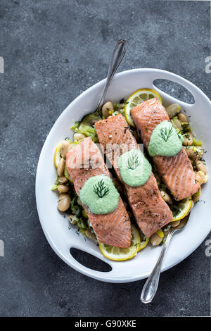 Eine Platte, weiße Butter Bohnen mit Backofen gekrönt, Gebackener Lachs, die Scheiben von oben fotografiert werden. Stockfoto