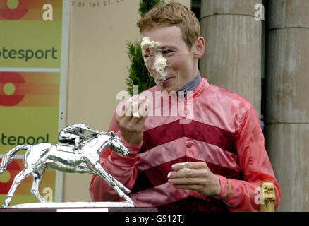 Jamie Spencer, der Champion von 2005, wischt sich die Creme ab, nachdem Tony Culhane ihn auf der Rennbahn von Doncaster mit einem Kuchen im Gesicht überrascht hatte Stockfoto