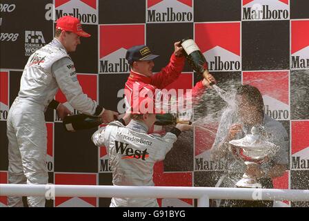 Mika Hakkinen (vorne Mitte) Feiert seinen Sieg mit David Coulthard (L) & Michael Schumacher (Hinten in der Mitte), da Mansour Ojjeh mit Champagner bedeckt ist (R) Stockfoto