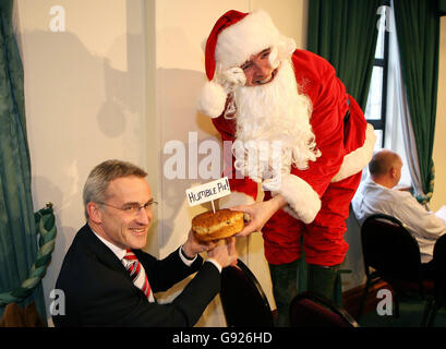 Michael O'Leary, Chief Executive von Ryanair, übergibt Vincent Wall of Dublin Airport Authority während einer Pressekonferenz in Dublin am Mittwoch, dem 21. Dezember 2005, ein Weihnachtsgebun mit der Bezeichnung "Humble Pie", bei dem bekannt gegeben wurde, dass die Billigfluggesellschaft eine massive Ausweitung des Flugbetriebs am Flughafen Dublin plant, Mit 18 neuen Routen zu Städten in ganz Europa. Der Billiganbieter wird im April und Mai 10 Länder mit 250 Arbeitsplätzen in Dublin unterstützen. Siehe PA Story TRANSPORT Ryanair Irland. DRÜCKEN Sie VERBANDSFOTO. Bildnachweis sollte lauten: Julien Behal/PA Stockfoto