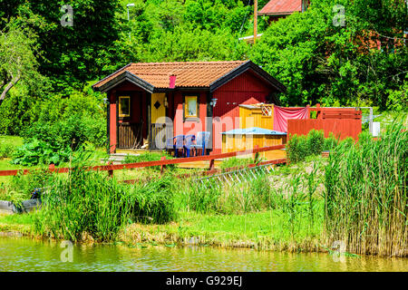 Bjornavad, Schweden - 20. Juni 2016: Kleines Gehöft am Göta-Kanal. Das Haus ist rot mit schwarzen Details. Kanal in Fron sichtbar Stockfoto