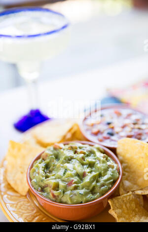 Guacamole und Chips mit Margarita im Hintergrund. Stockfoto