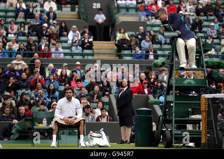 Der Obmann spricht mit Gilles Simon über die Feuchtigkeit auf dem Platz in seinem Match gegen Grigor Dimitrov an Tag drei der Wimbledon Championships bei den All England Lawn Tennis and Croquet Club, Wimbledon. Stockfoto