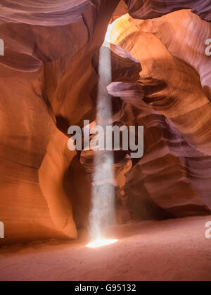Mittag in rot-Orange Antelope Canyon. Ein dünner Strahl des Tageslichtes leuchtet auf dem sandigen Boden des Canyons Stockfoto