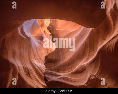 Mittag in rot-Orange Antelope Canyon. Ein dünner Strahl des Tageslichtes leuchtet auf dem sandigen Boden des Canyons Stockfoto