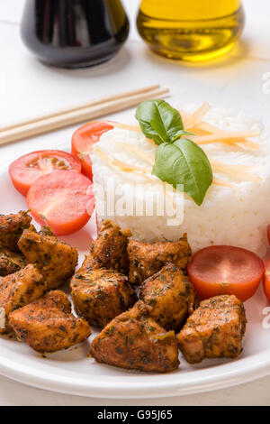 Huhn mit Reis und Tomaten auf weißen Teller Stockfoto