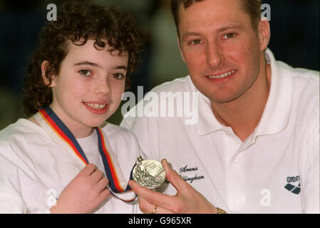 Nick Gilligham lässt den jungen Schwimmer Chantal Carr, 9, aus Glasgow, seine olympische Silbermedaille für die Größe ausprobieren, als er seine Rückkehr zum Wettkampfschwimmen bei der Schwimmweltmeisterschaft in Glasgow ankündigt Stockfoto