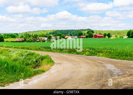 Loddby, Schweden – 20. Juni 2016: Das Dorf der Loddby aus einer Gabel in der Straße gesehen. Wald in den Feldern im Vordergrund und Hintergrund Stockfoto