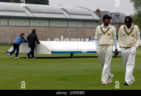 Die Bodenmitarbeiter bringen die Regenabdeckung zum Vorliegen, als Sri Lanka am zweiten Tag des Tourmatches gegen britische Universitäten im Fenners Cricket Ground in Cambridge, Cambridgeshire, das Feld verlässt. Stockfoto